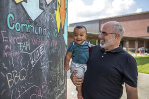 Man Holding Baby looking at community art